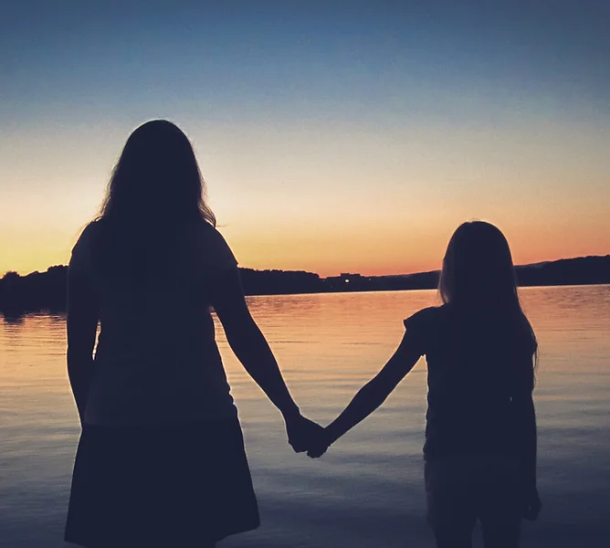 Woman and Child Holding Hands at Sunset